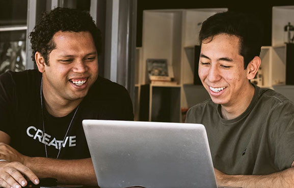 Two business people using laptop in lobby