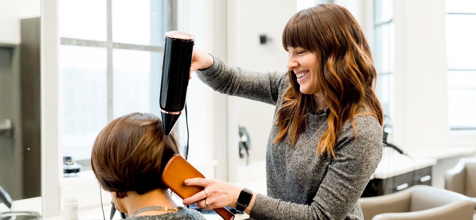 Hairdresser blow drying client's hair
