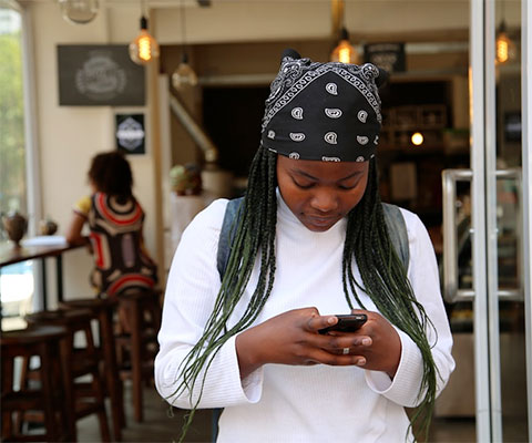 Young woman using phone in lobby